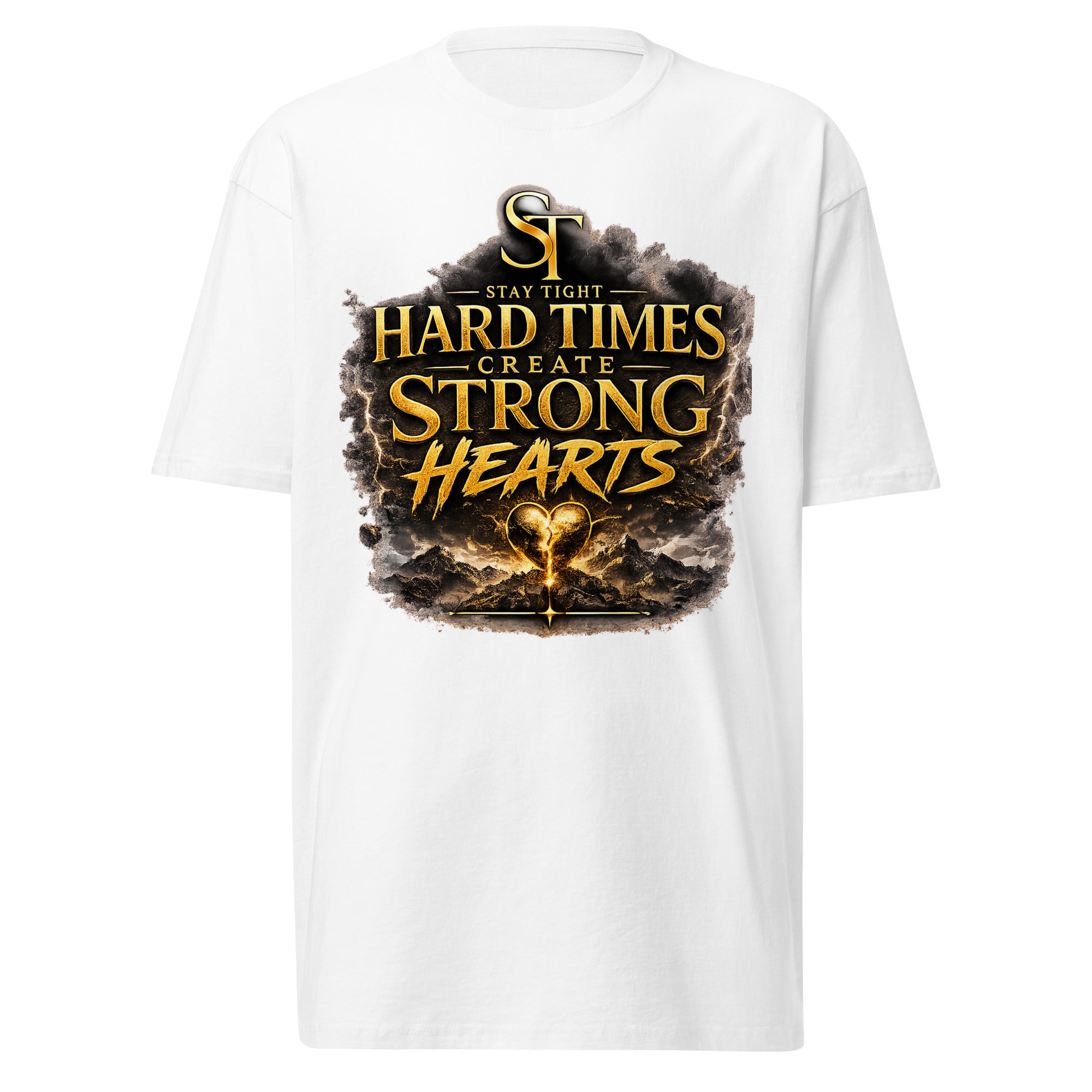 Stay Tight premium heavyweight T-shirt featuring the motivational phrase "Hard Times Create Strong Hearts" in bold gold lettering above a glowing heart surrounded by rugged mountains and storm clouds, symbolizing resilience, perseverance, courage, inner strength, and overcoming adversity.